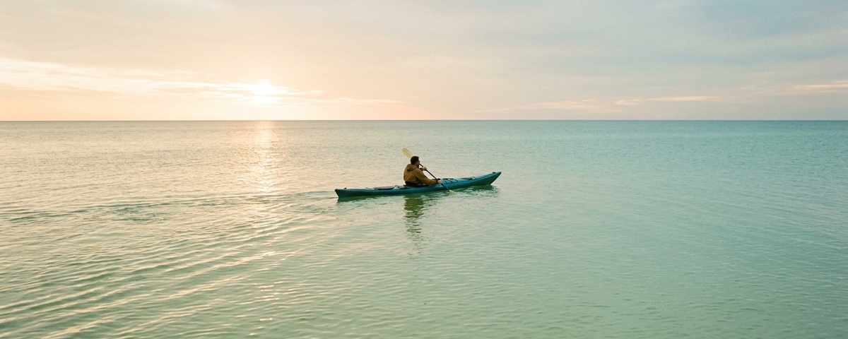 Lone kayaker paddling in turquoise waters at sunrise on Anna Maria Island winter rental destination