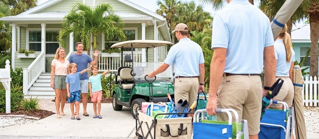 rental staff in blue polo shirts hand-deliver beach gear to a family outside a pastel Florida vacation cottage.